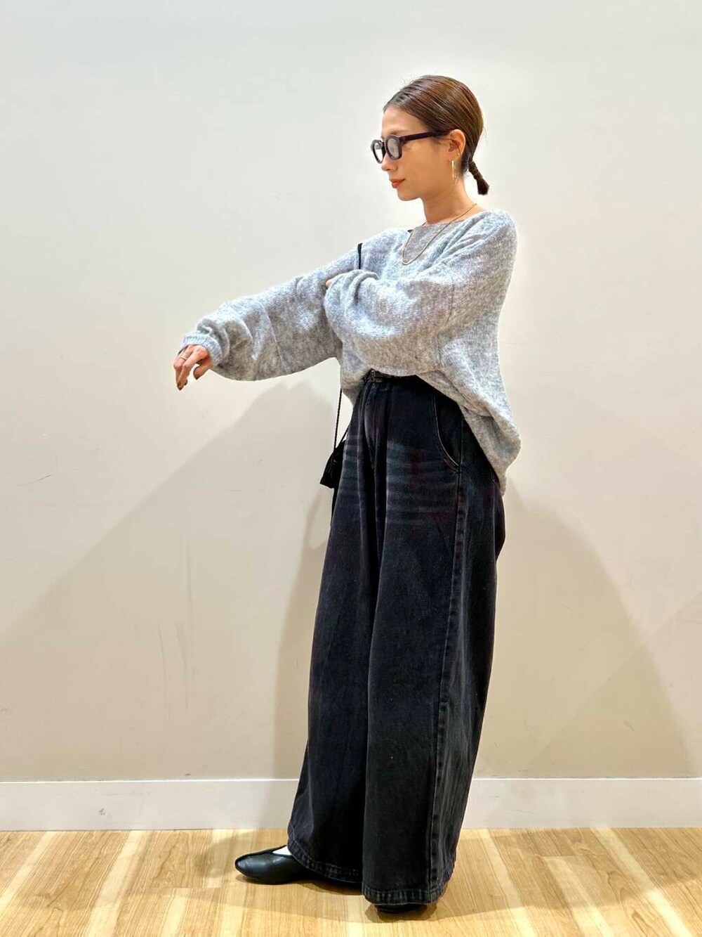 ブラック系のショルダーバッグ、ブラック系のデニムパンツ、グレー系のニット/セーターを着用したレディースの春コーディネートの2枚目の写真