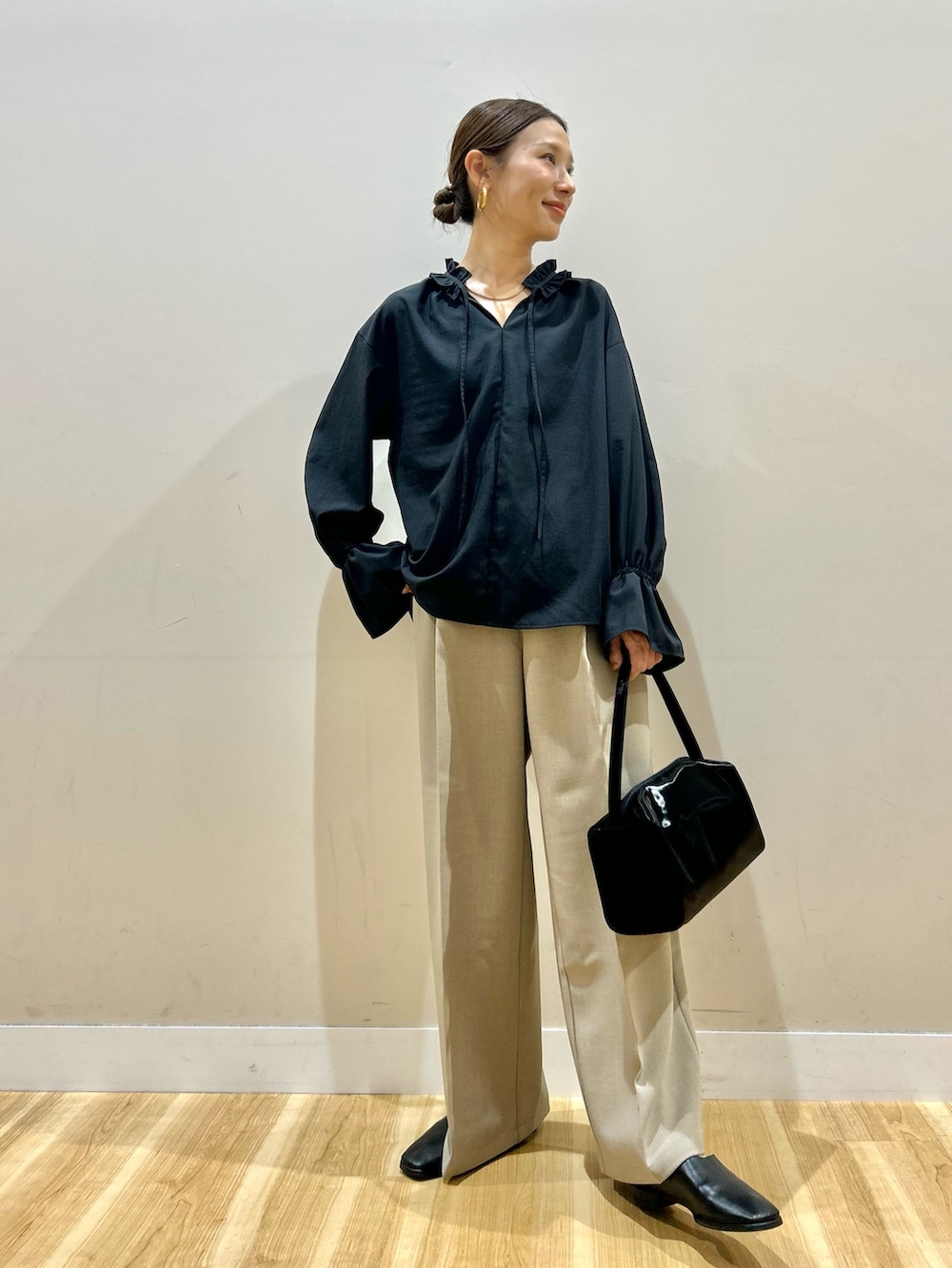 ブラック系のシャツ/ブラウス、ブラック系のトートバッグ、ベージュ系のその他パンツを着用したレディースの春コーディネートの5枚目の写真