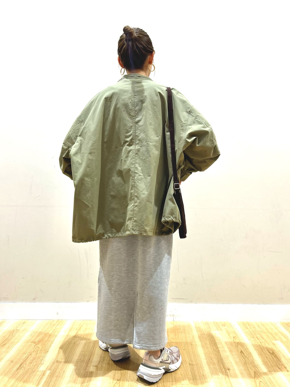 グリーン系のモッズコート、グレー系のワンピース、ブラウン系のショルダーバッグを着用したレディースの春コーディネートの3枚目の写真