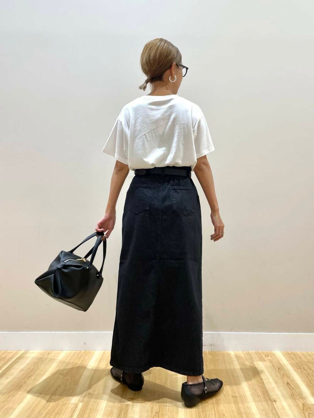 ブラック系のハンドバッグ、ブラック系のその他シューズ、ホワイト系のTシャツ/カットソーを着用したレディースの夏コーディネートの6枚目の写真