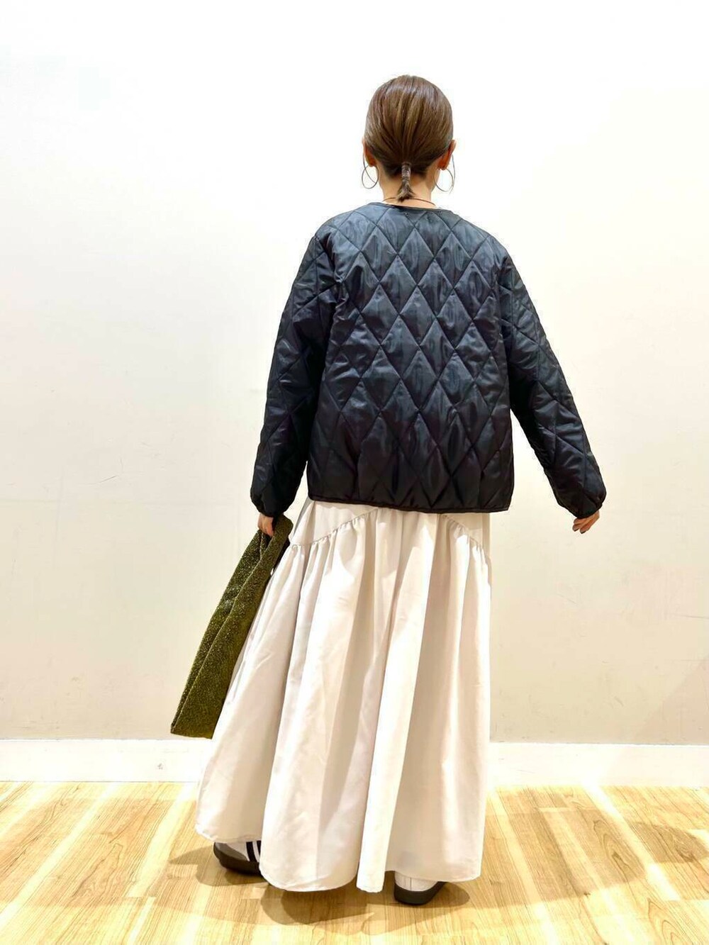 ゴールド系のトートバッグ、グレー系のワンピース、ブラック系のマウンテンパーカーを着用したレディースの冬コーディネートの10枚目の写真