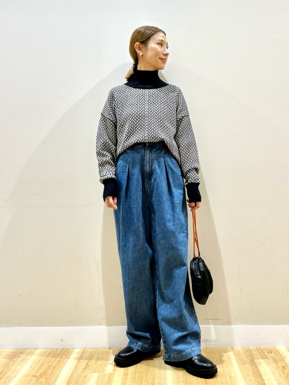 ブラック系のノーカラージャケット、ホワイト系のニット/セーター、ブルー系のデニムパンツを着用したレディースの秋コーディネートの4枚目の写真