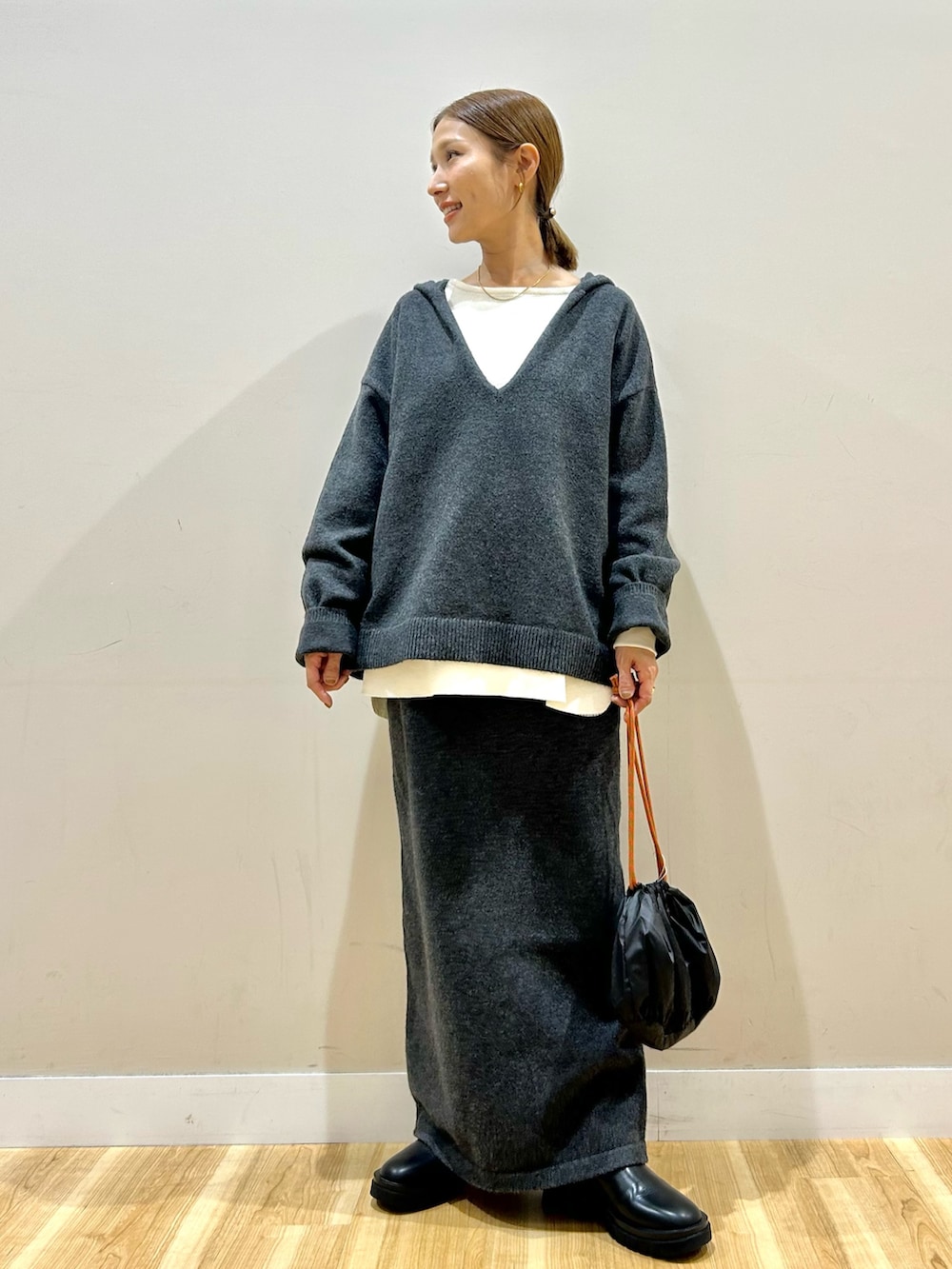 グレー系のニット/セーター、ホワイト系のTシャツ/カットソー、グレー系のスカートを着用したレディースの秋コーディネートの4枚目の写真