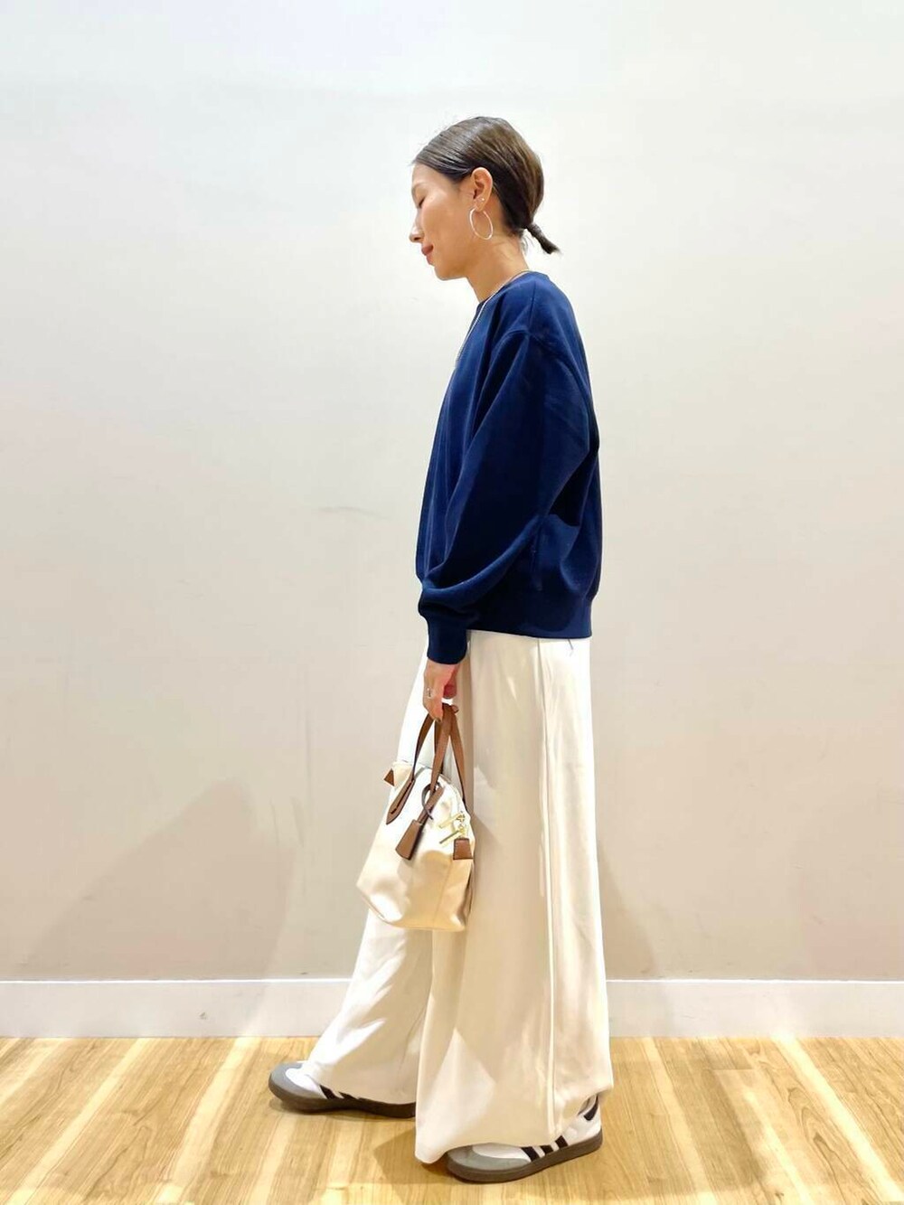 ホワイト系のトートバッグ、ブルー系のスウェット、ホワイト系のスニーカーを着用したレディースの秋コーディネートの5枚目の写真