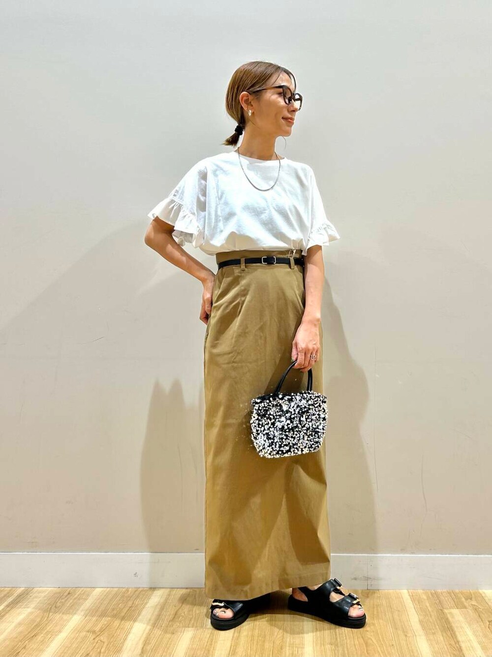 シルバー系のショルダーバッグ、ブラック系のサンダル、ホワイト系のTシャツ/カットソーを着用したレディースの春コーディネートの6枚目の写真