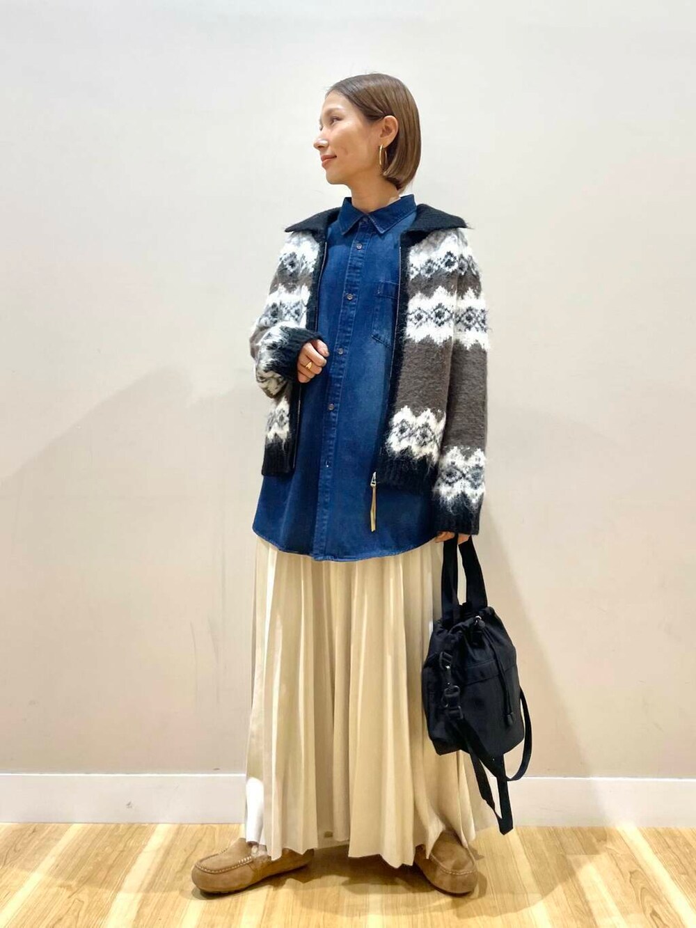 ブラック系のショルダーバッグ、ベージュ系のスカート、ブラウン系のカーディガン/ボレロを着用したレディースの秋コーディネートの5枚目の写真