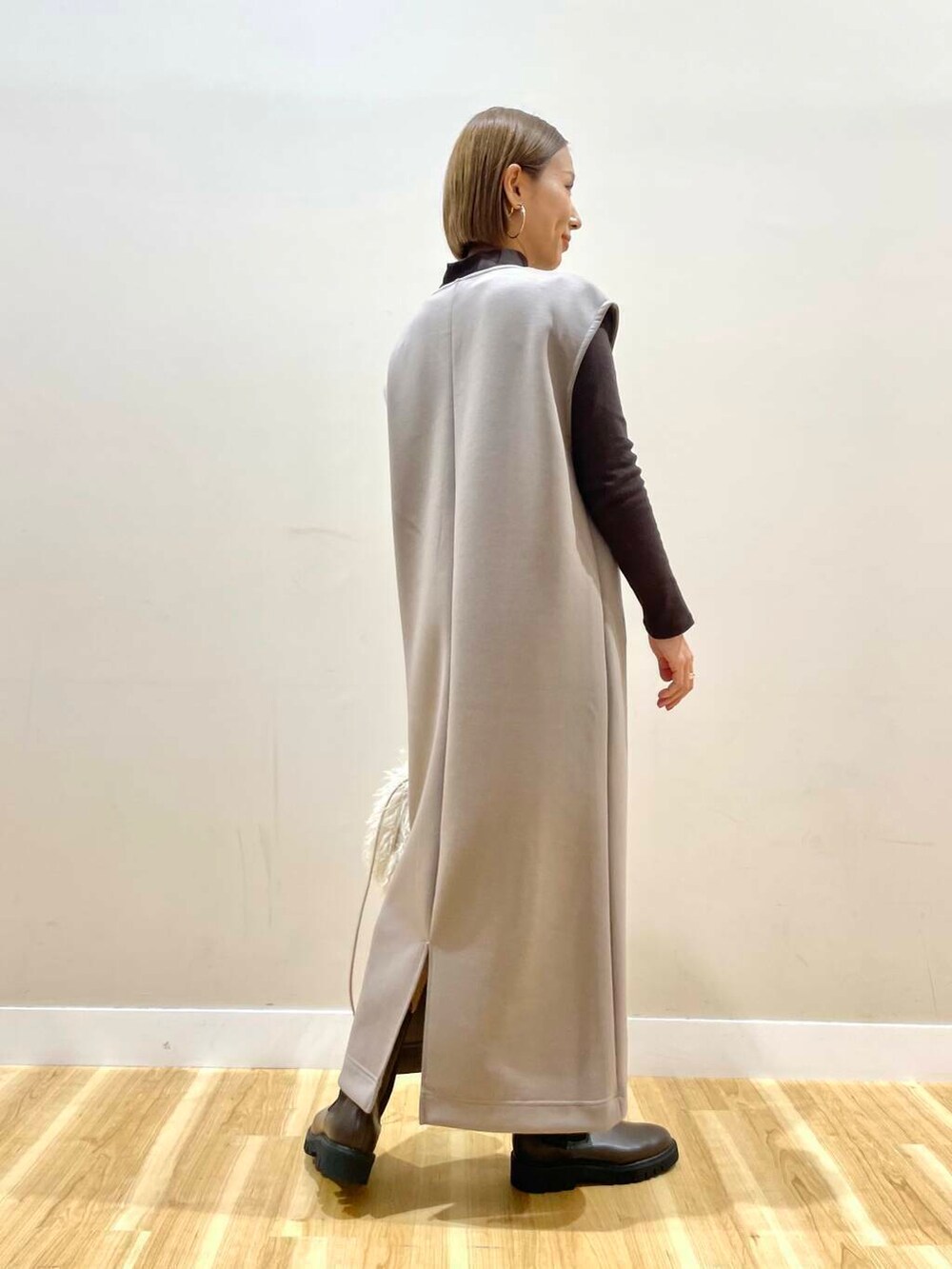 ブラウン系のブーツ、ベージュ系のショルダーバッグ、ブラウン系のジャンパースカートを着用したレディースの秋コーディネートの3枚目の写真