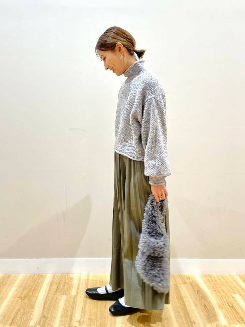 ブラック系のパンプス、グリーン系のスカート、グレー系のハンドバッグを着用したレディースの冬コーディネートの8枚目の写真