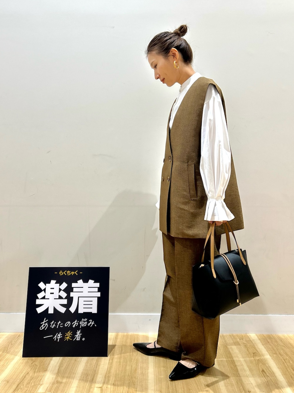 ブラウン系のセットアップ、ホワイト系のシャツ/ブラウス、ブラック系のトートバッグを着用したレディースの春コーディネートの2枚目の写真