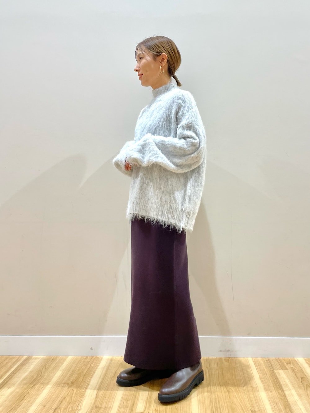 ホワイト系のダウンジャケット/コート、グレー系のニット/セーター、ブラウン系のスカートを着用したレディースの冬コーディネートの7枚目の写真