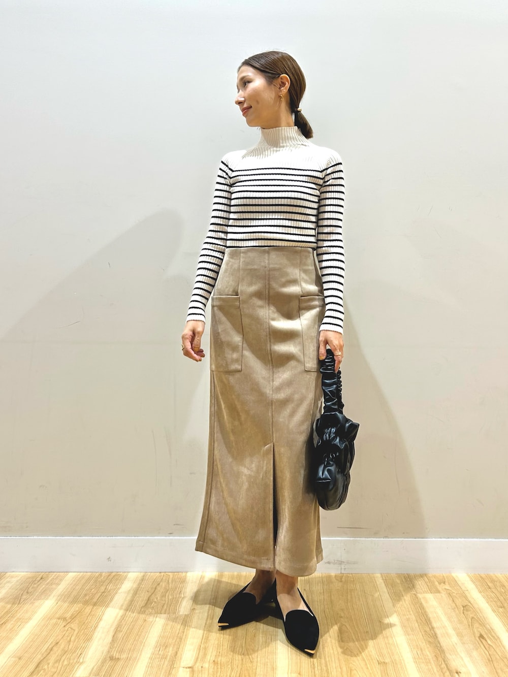 ブラック系のベスト、ホワイト系のニット/セーター、ブラウン系のスカートを着用したレディースの秋コーディネートの4枚目の写真