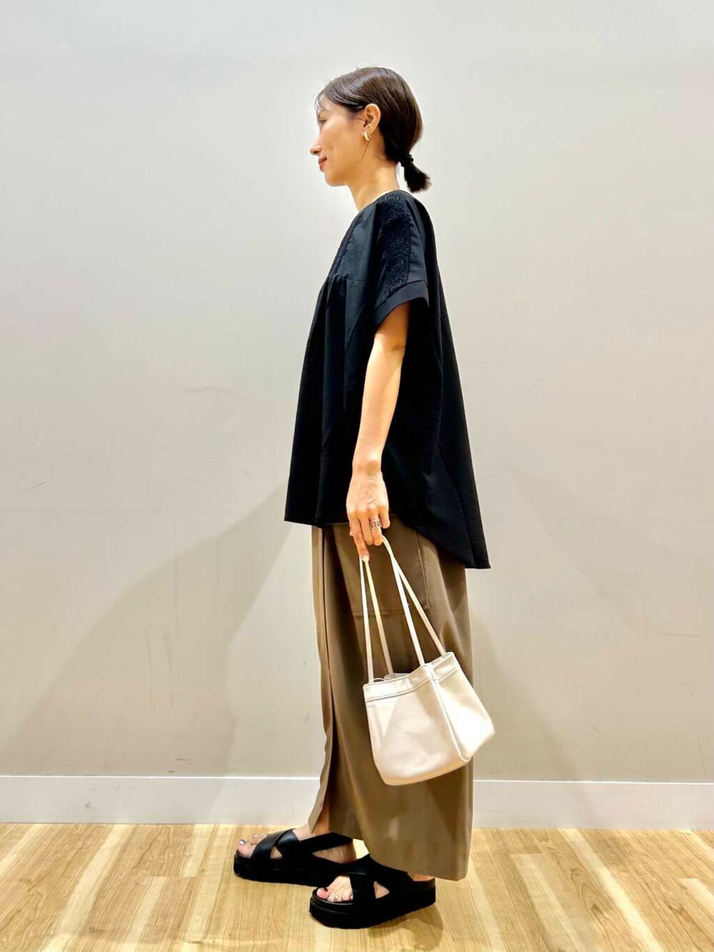 ブラック系のシャツ/ブラウス、ホワイト系のハンドバッグ、ブラック系のサンダルを着用したレディースの夏コーディネートの2枚目の写真