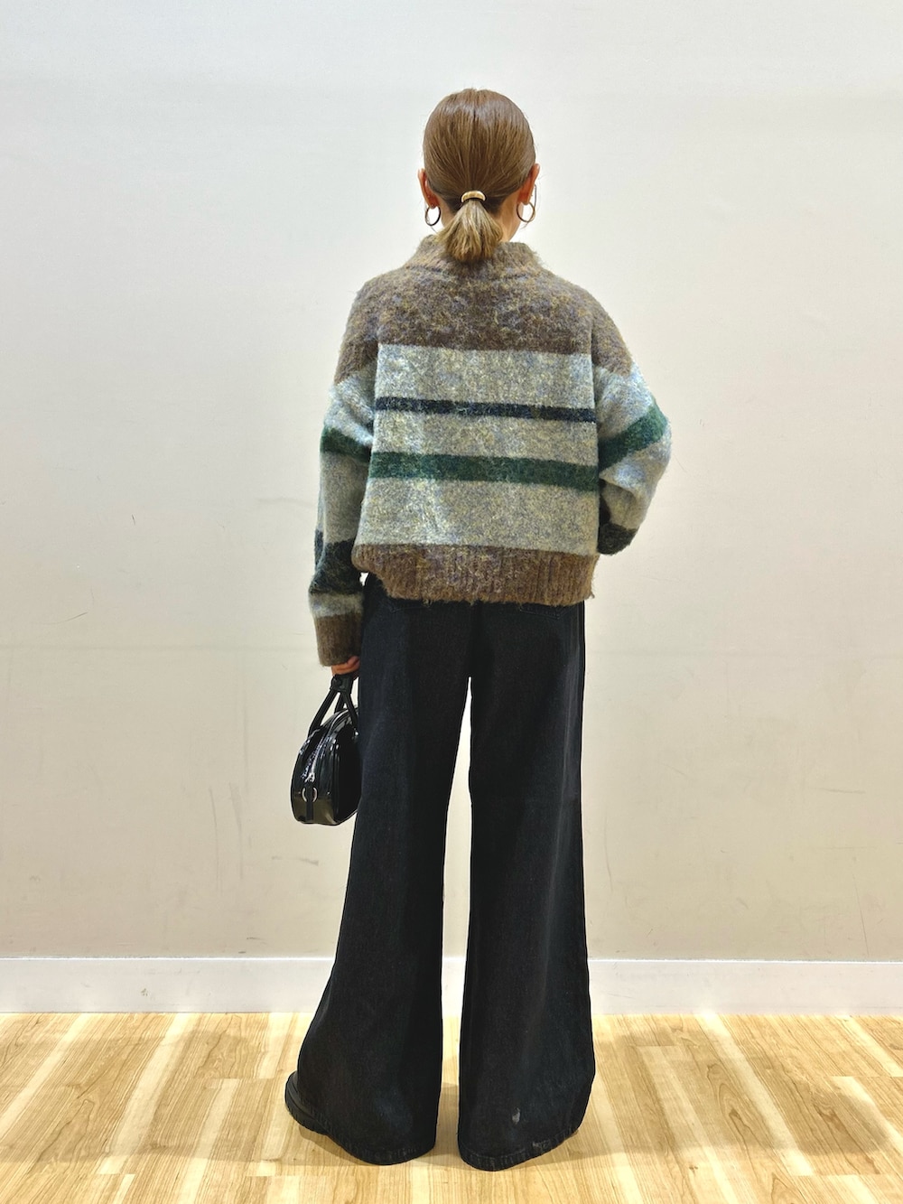 ブラウン系のニット/セーター、ブラック系のデニムパンツ、ブラック系のボストンバッグを着用したレディースの秋コーディネートの4枚目の写真