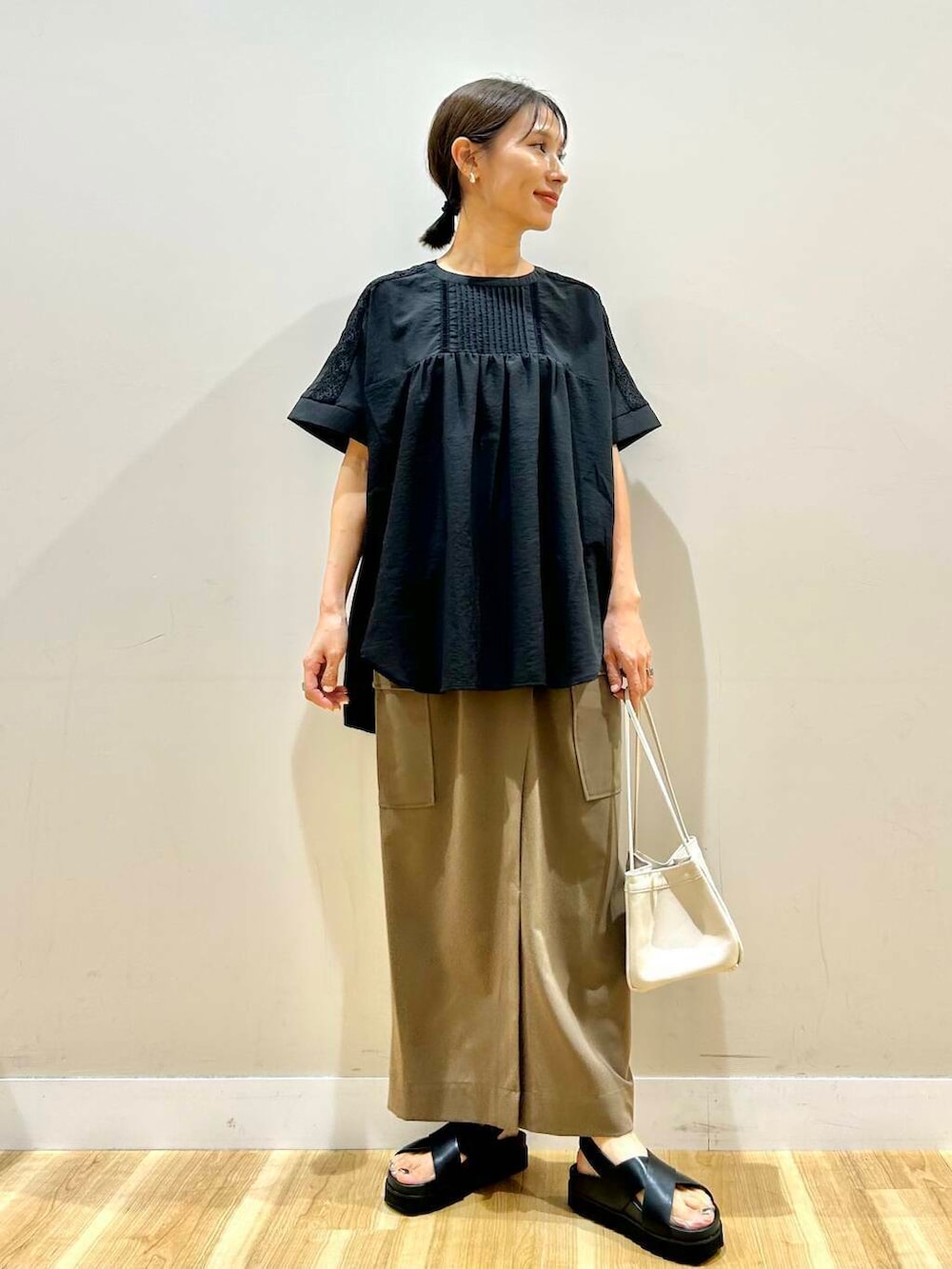 ブラック系のシャツ/ブラウス、ホワイト系のハンドバッグ、ブラック系のサンダルを着用したレディースの夏コーディネートの5枚目の写真