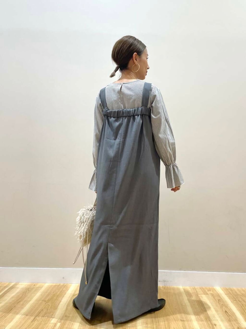 ベージュ系のショルダーバッグ、グレー系のジャンパースカートを着用したレディースの秋コーディネートの3枚目の写真