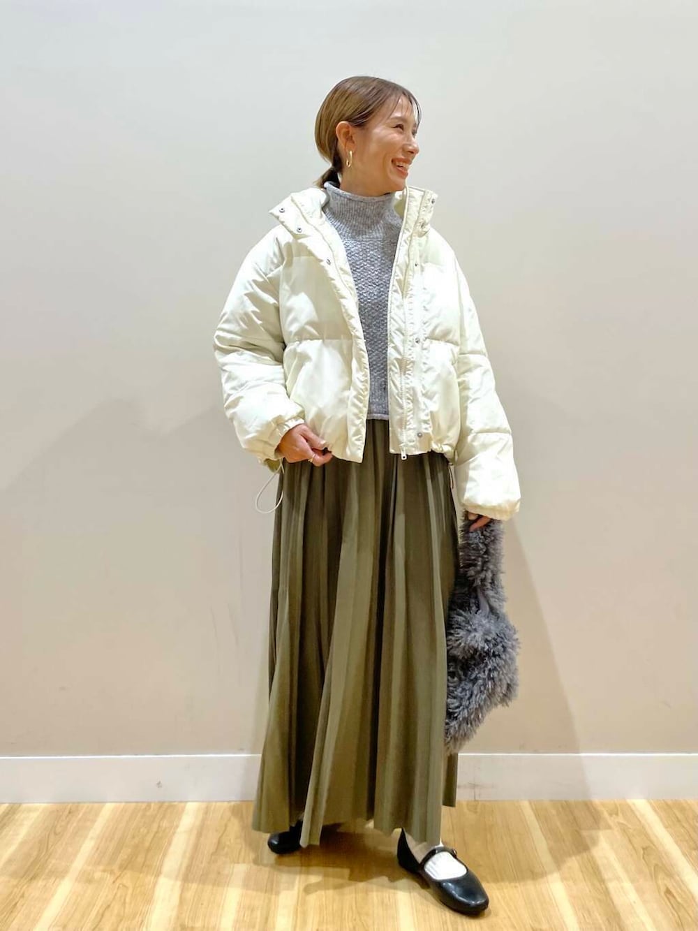 ブラック系のパンプス、グリーン系のスカート、グレー系のハンドバッグを着用したレディースの冬コーディネートの6枚目の写真