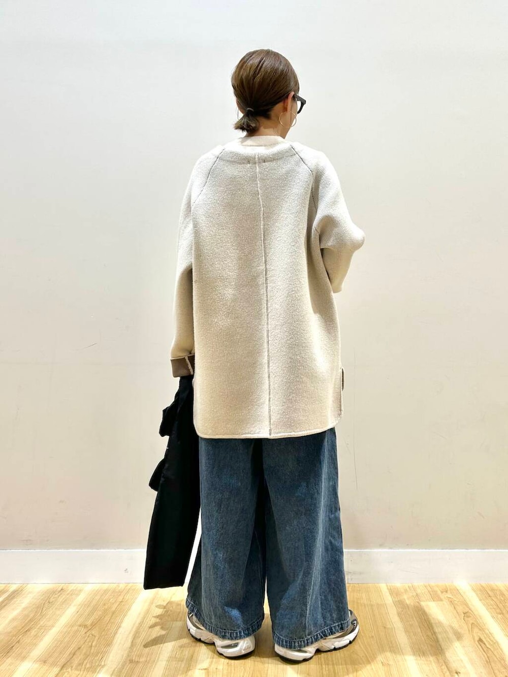 ホワイト系のニット/セーター、ブルー系のデニムパンツ、ブラック系のトートバッグを着用したレディースの春コーディネートの3枚目の写真
