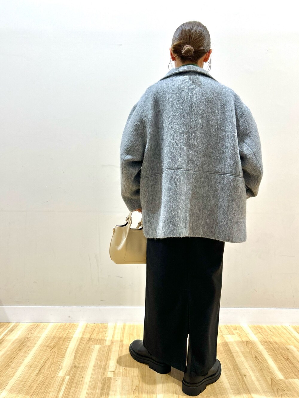 グレー系のその他アウター、グリーン系のニット/セーター、ブラック系のジャンパースカートを着用したレディースの冬コーディネートの4枚目の写真