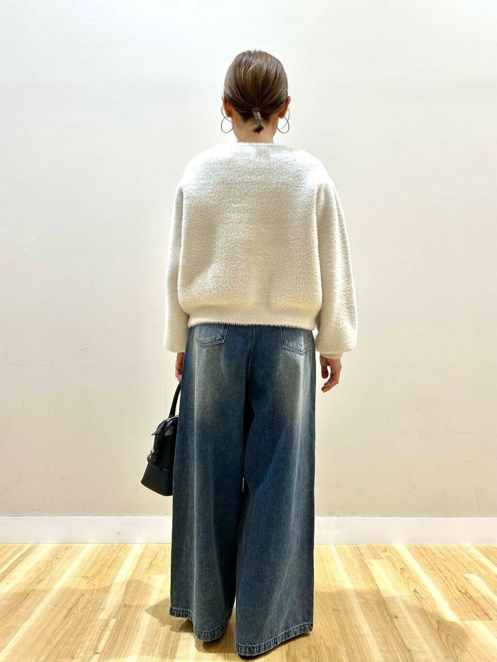 ブラック系のボストンバッグ、ブラック系のパンプス、ホワイト系のカーディガン/ボレロを着用したレディースの冬コーディネートの2枚目の写真