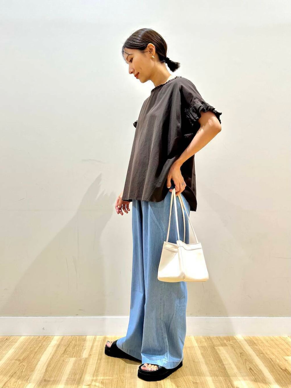 ホワイト系のハンドバッグ、ブラック系のサンダル、ブラウン系のシャツ/ブラウスを着用したレディースの夏コーディネートの2枚目の写真