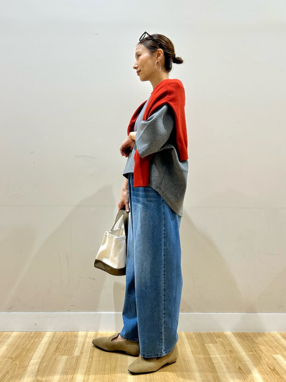 レッド系のニット/セーター、グレー系のTシャツ/カットソー、グレー系のトートバッグを着用したレディースの秋コーディネートの4枚目の写真