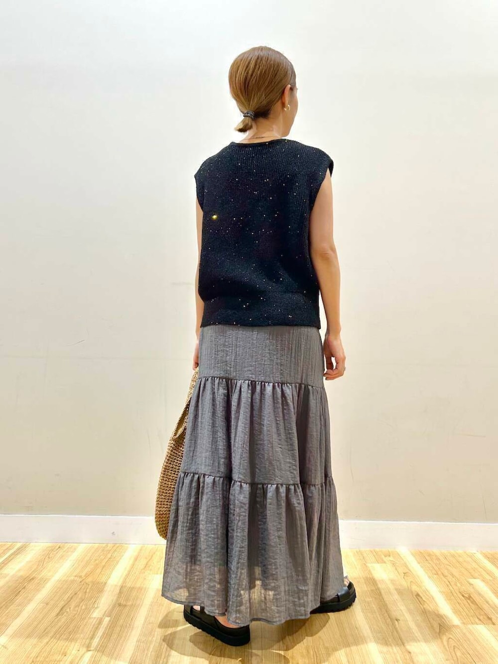 イエロー系のトートバッグ、ブラック系のサンダル、ブラック系のベストを着用したレディースの夏コーディネートの3枚目の写真