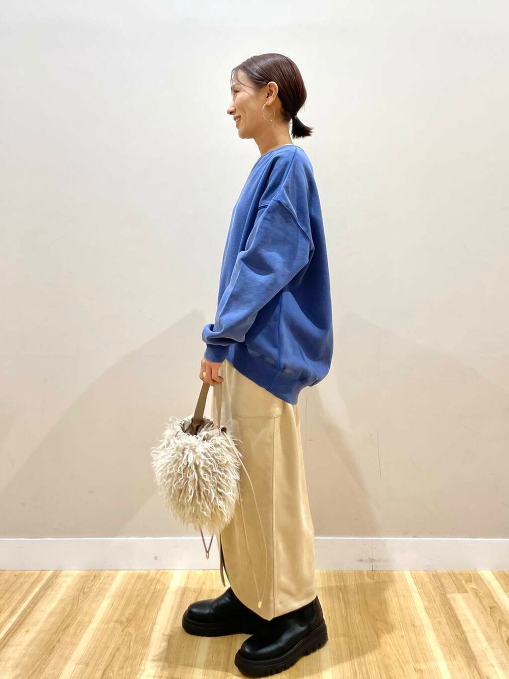 ベージュ系のショルダーバッグ、ホワイト系のスカート、グレー系のパーカーを着用したレディースの冬コーディネートの5枚目の写真