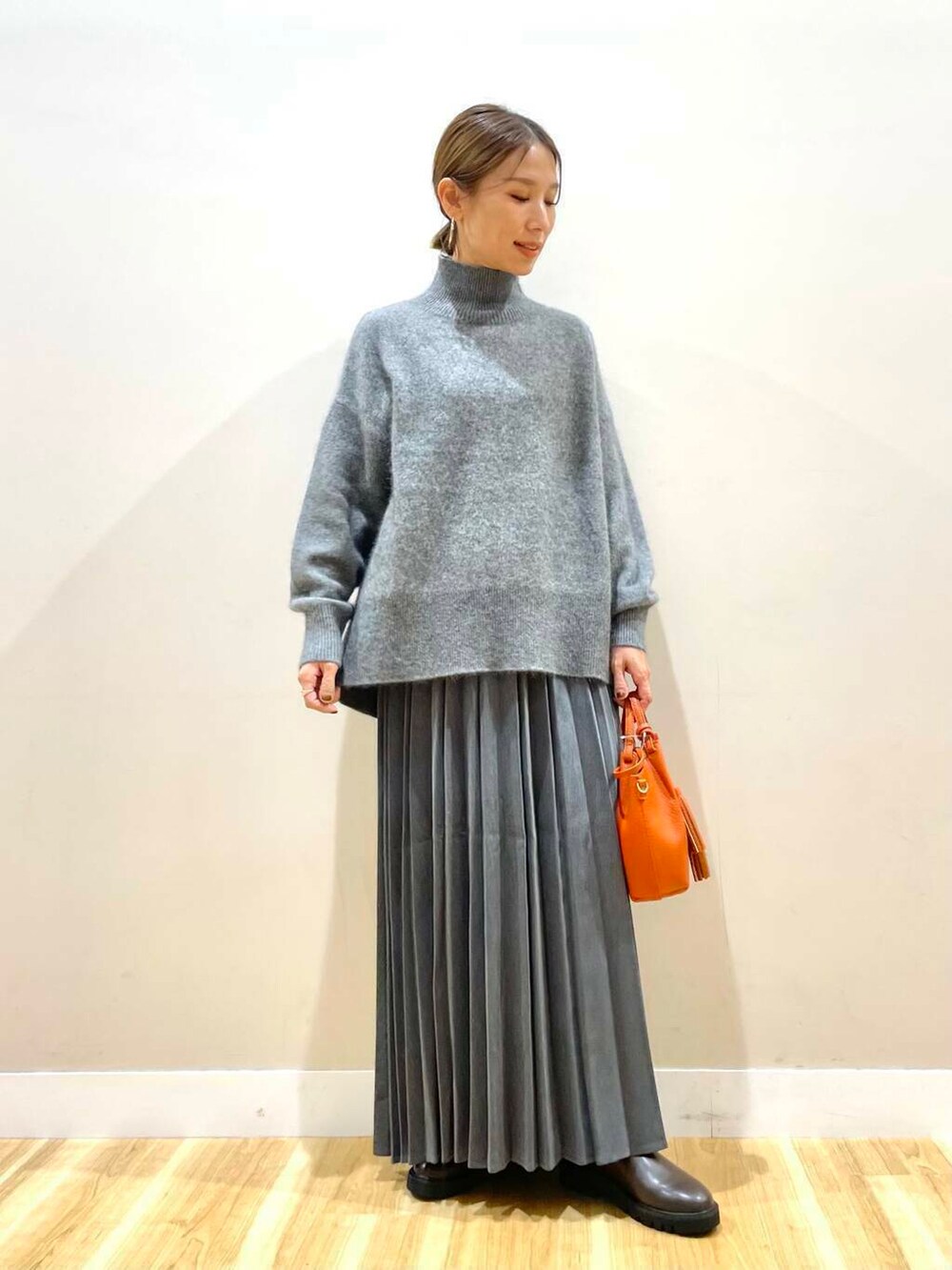 ブラウン系のブーツ、オレンジ系のショルダーバッグ、グレー系のスカートを着用したレディースの冬コーディネートの6枚目の写真