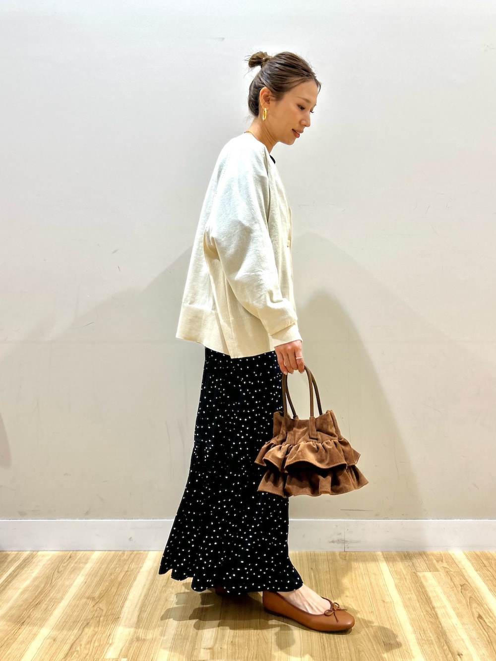 ブラック系のスウェット、ブラック系のスカート、ブラウン系のハンドバッグを着用したレディースの春コーディネートの2枚目の写真