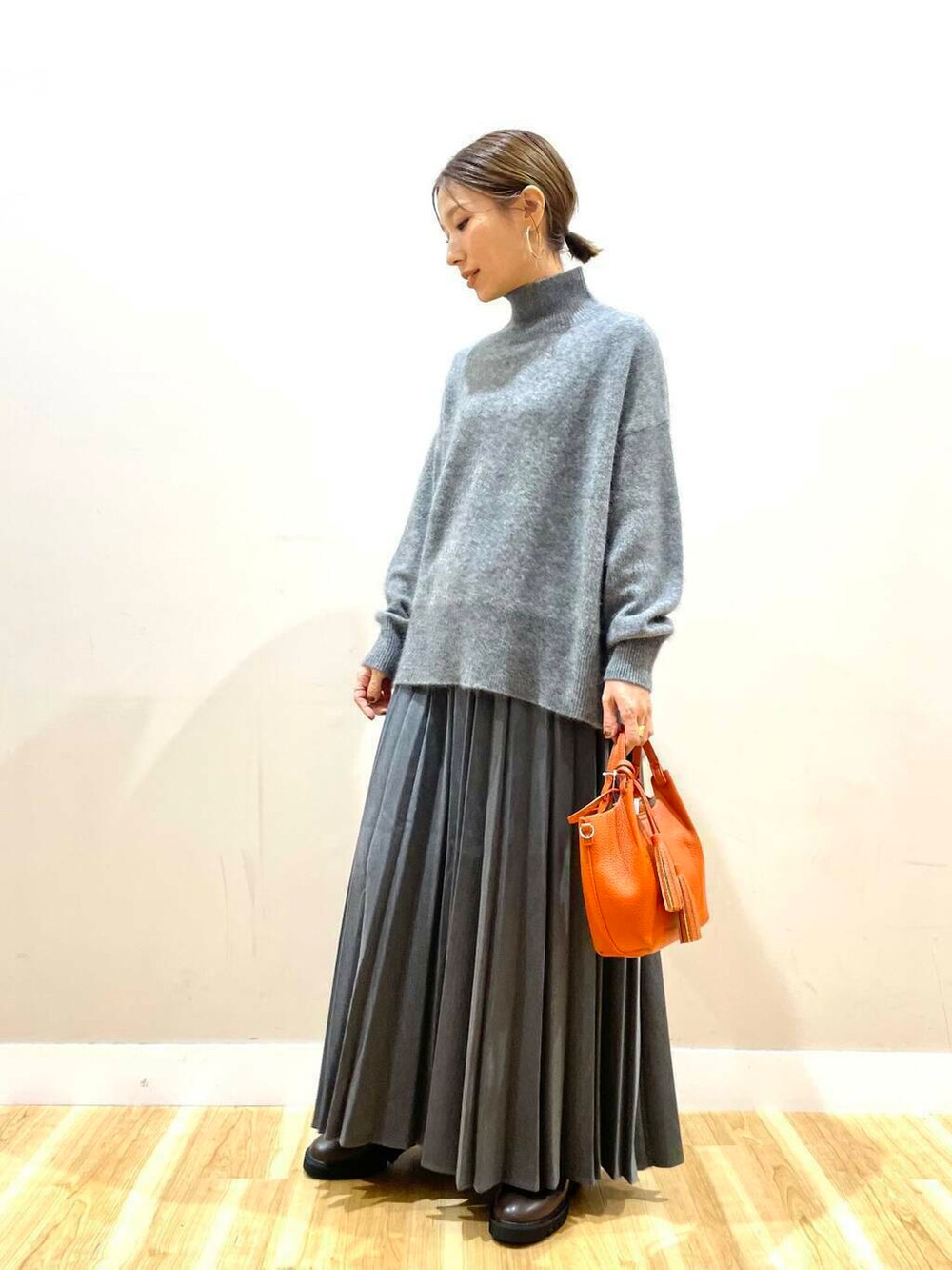 ブラウン系のブーツ、オレンジ系のショルダーバッグ、グレー系のスカートを着用したレディースの冬コーディネートの9枚目の写真