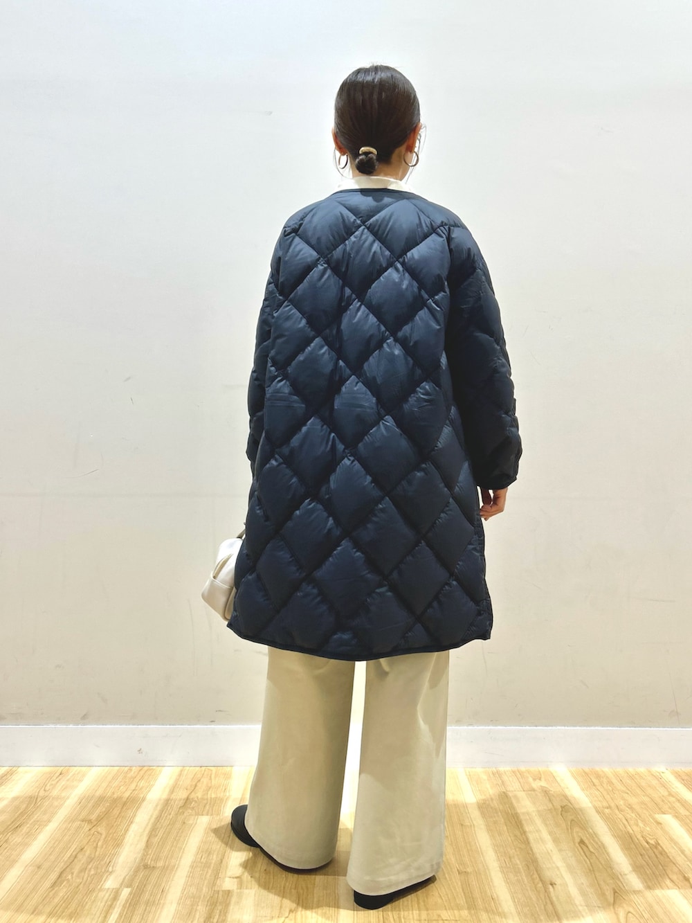 ブルー系のダウンジャケット/コート、ホワイト系のニット/セーター、ベージュ系のその他パンツを着用したレディースの冬コーディネートの3枚目の写真