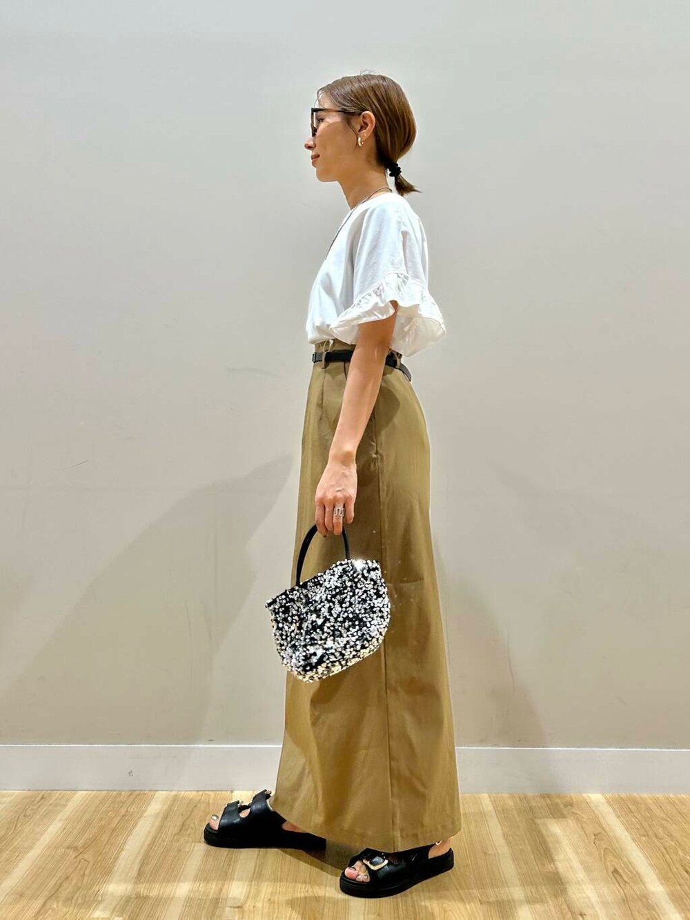 シルバー系のショルダーバッグ、ブラック系のサンダル、ホワイト系のTシャツ/カットソーを着用したレディースの春コーディネートの3枚目の写真