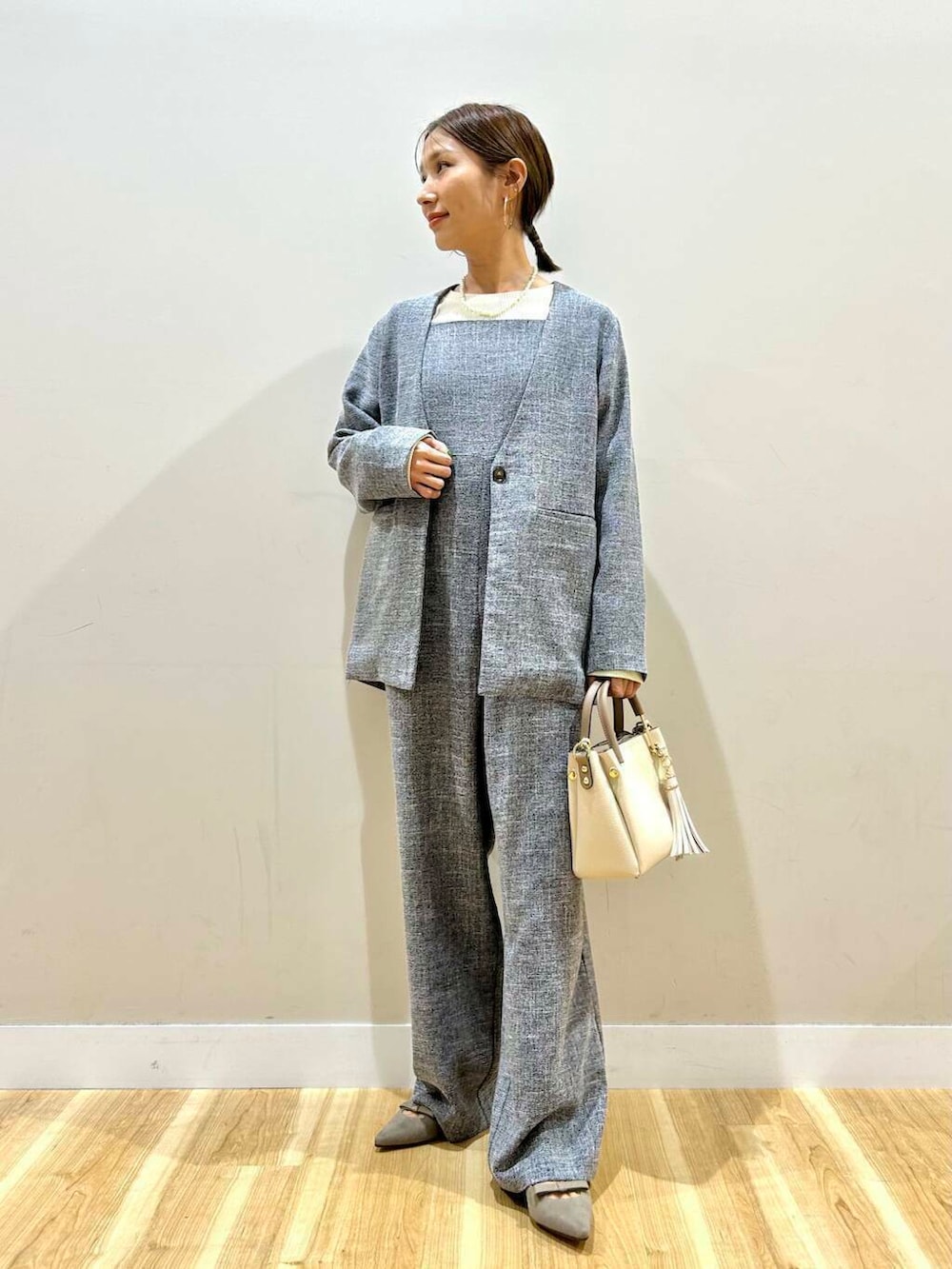 ホワイト系のトートバッグ、グレー系のパンプス、ブラック系のノーカラージャケットを着用したレディースの冬コーディネートの2枚目の写真