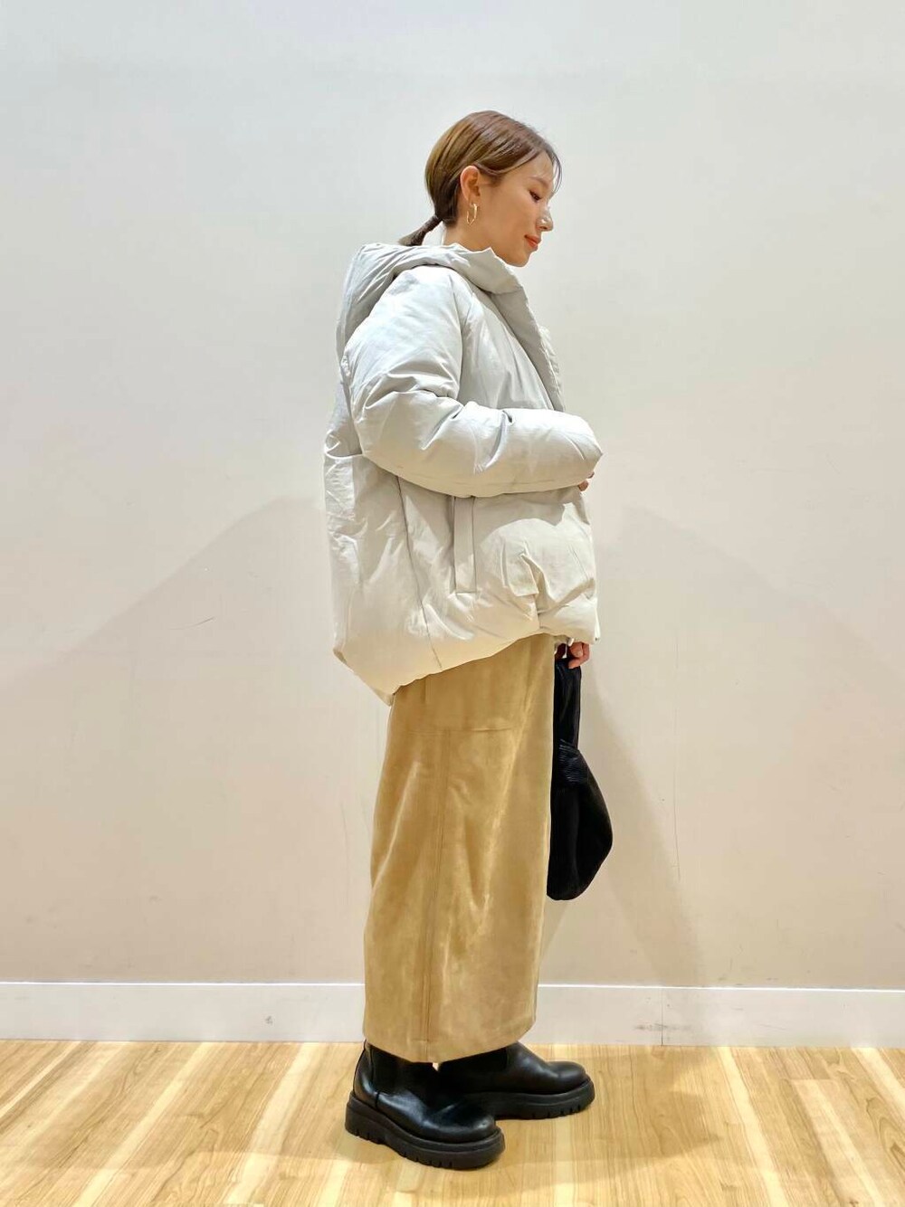 ブラウン系のスカート、ブラック系のハンドバッグ、グレー系のニット/セーターを着用したレディースの冬コーディネートの2枚目の写真