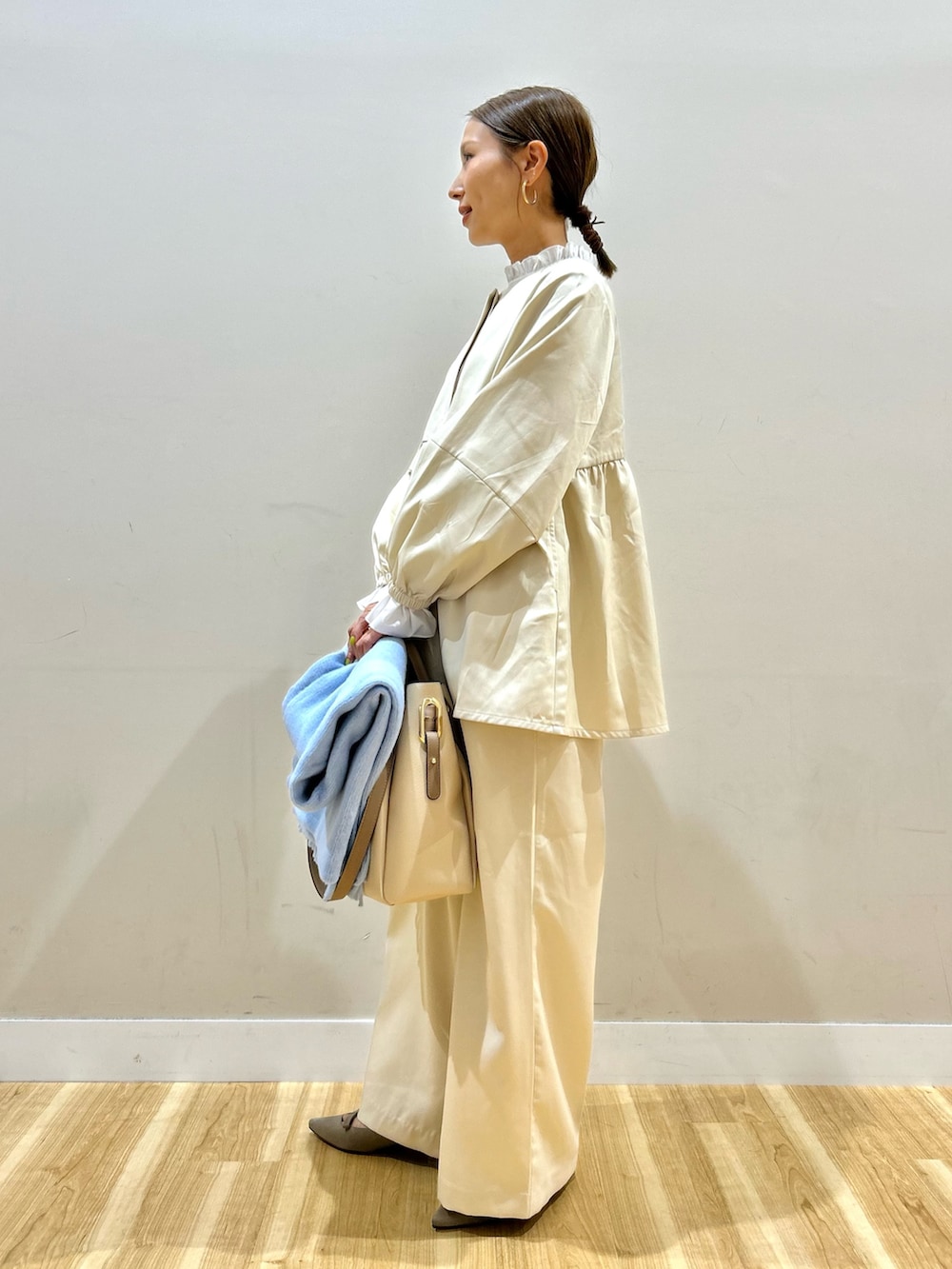 ベージュ系のセットアップ、ホワイト系のトートバッグを着用したレディースの秋コーディネートの2枚目の写真