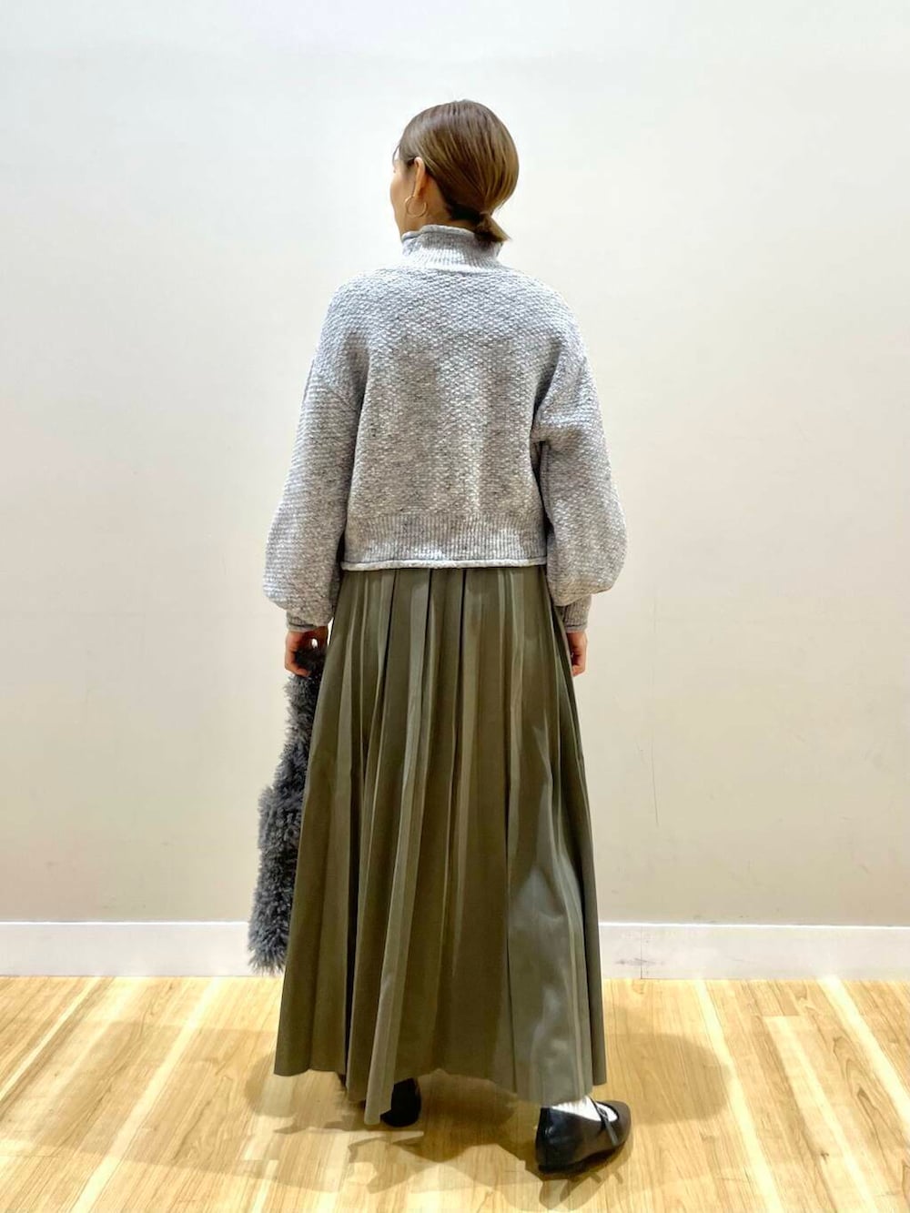 ブラック系のパンプス、グリーン系のスカート、グレー系のハンドバッグを着用したレディースの冬コーディネートの9枚目の写真