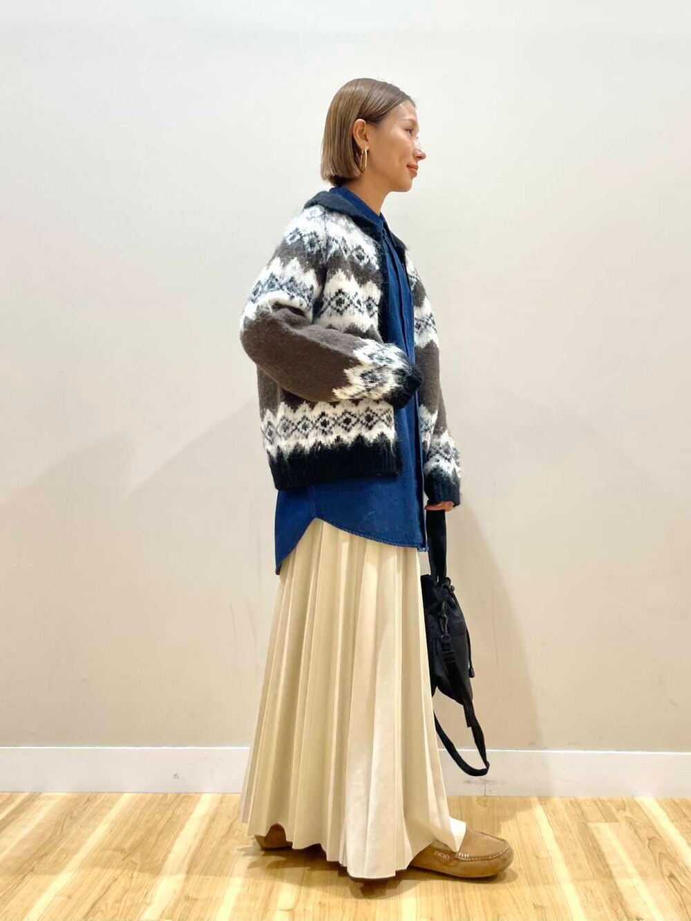 ブラック系のショルダーバッグ、ベージュ系のスカート、ブラウン系のカーディガン/ボレロを着用したレディースの秋コーディネートの4枚目の写真