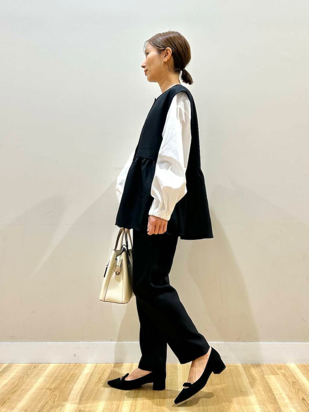 ホワイト系のトートバッグ、ブラック系のパンプス、ブラック系のセットアップを着用したレディースの冬コーディネートの2枚目の写真