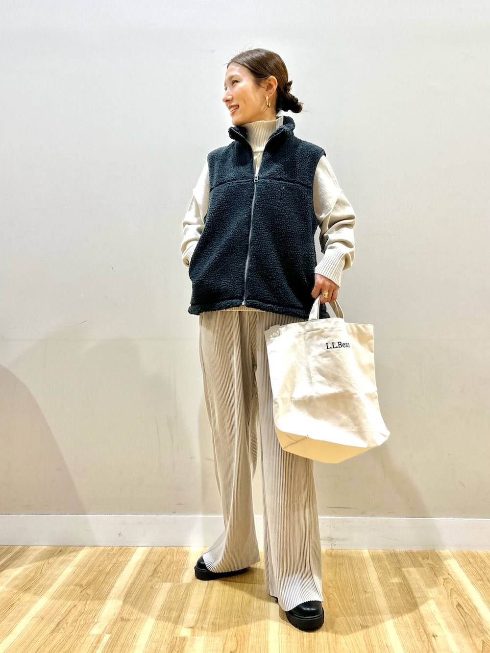 グレー系のベスト、グリーン系のダウンジャケット/コート、ホワイト系のニット/セーターを着用したレディースの冬コーディネートの4枚目の写真