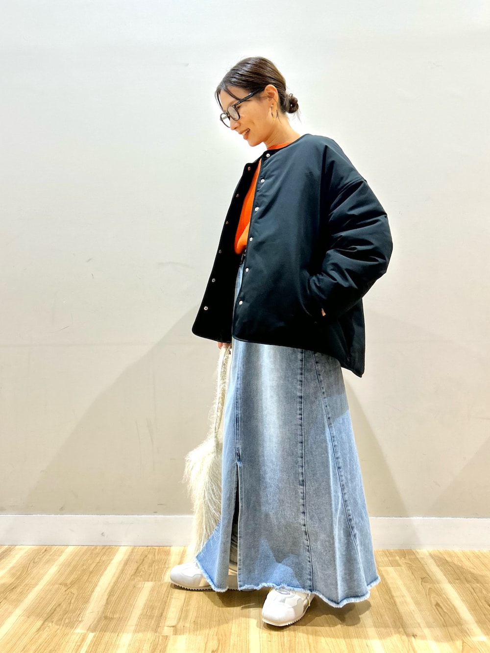 ブラック系のダウンジャケット/コート、オレンジ系のニット/セーター、ブルー系のスカートを着用したレディースの冬コーディネートの3枚目の写真