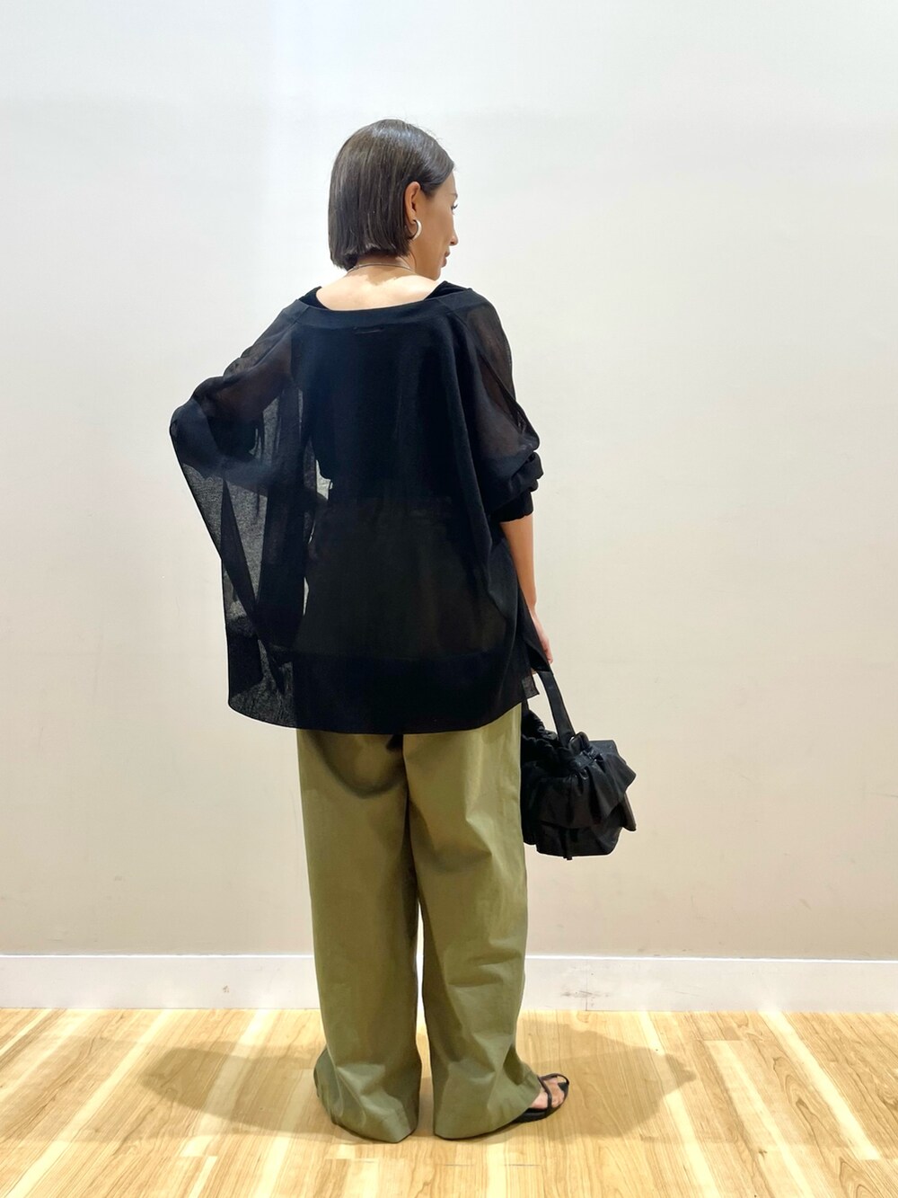 ブラック系のカーディガン/ボレロ、ブラック系のタンクトップ、グリーン系のチノパンツを着用したレディースの秋コーディネートの4枚目の写真