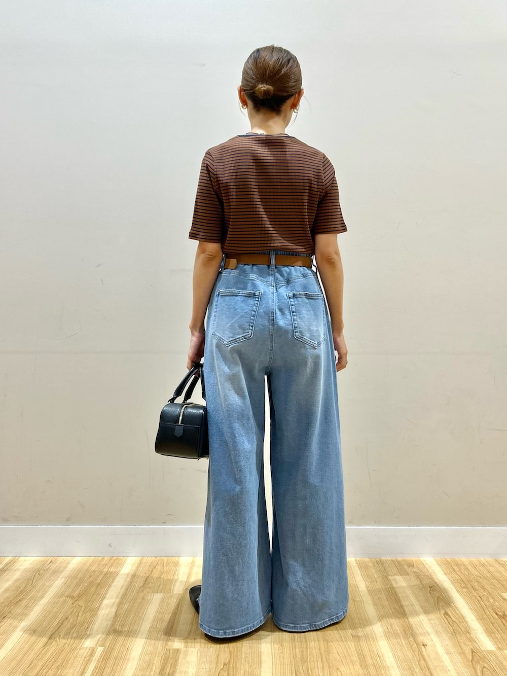 ブラウン系のTシャツ/カットソー、ブルー系のデニムパンツ、ブラック系のハンドバッグを着用したレディースの夏コーディネートの3枚目の写真