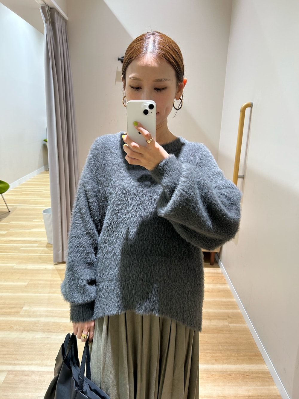 グレー系のニット/セーター、グリーン系のスカート、ブラック系のショルダーバッグを着用したレディースの秋コーディネートの5枚目の写真