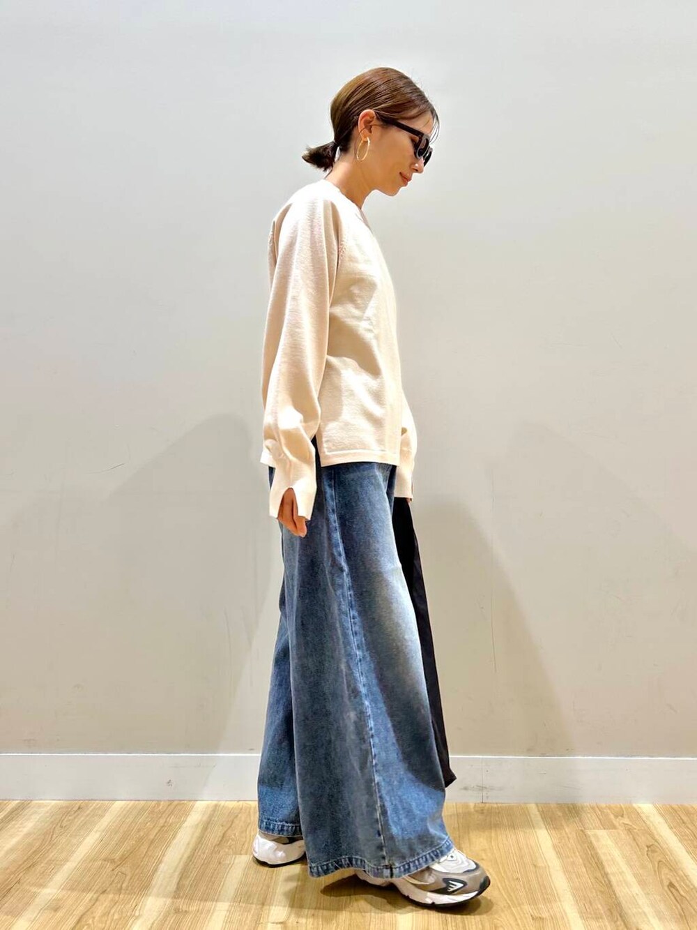 ホワイト系のニット/セーター、ブルー系のデニムパンツ、ブラック系のトートバッグを着用したレディースの春コーディネートの7枚目の写真
