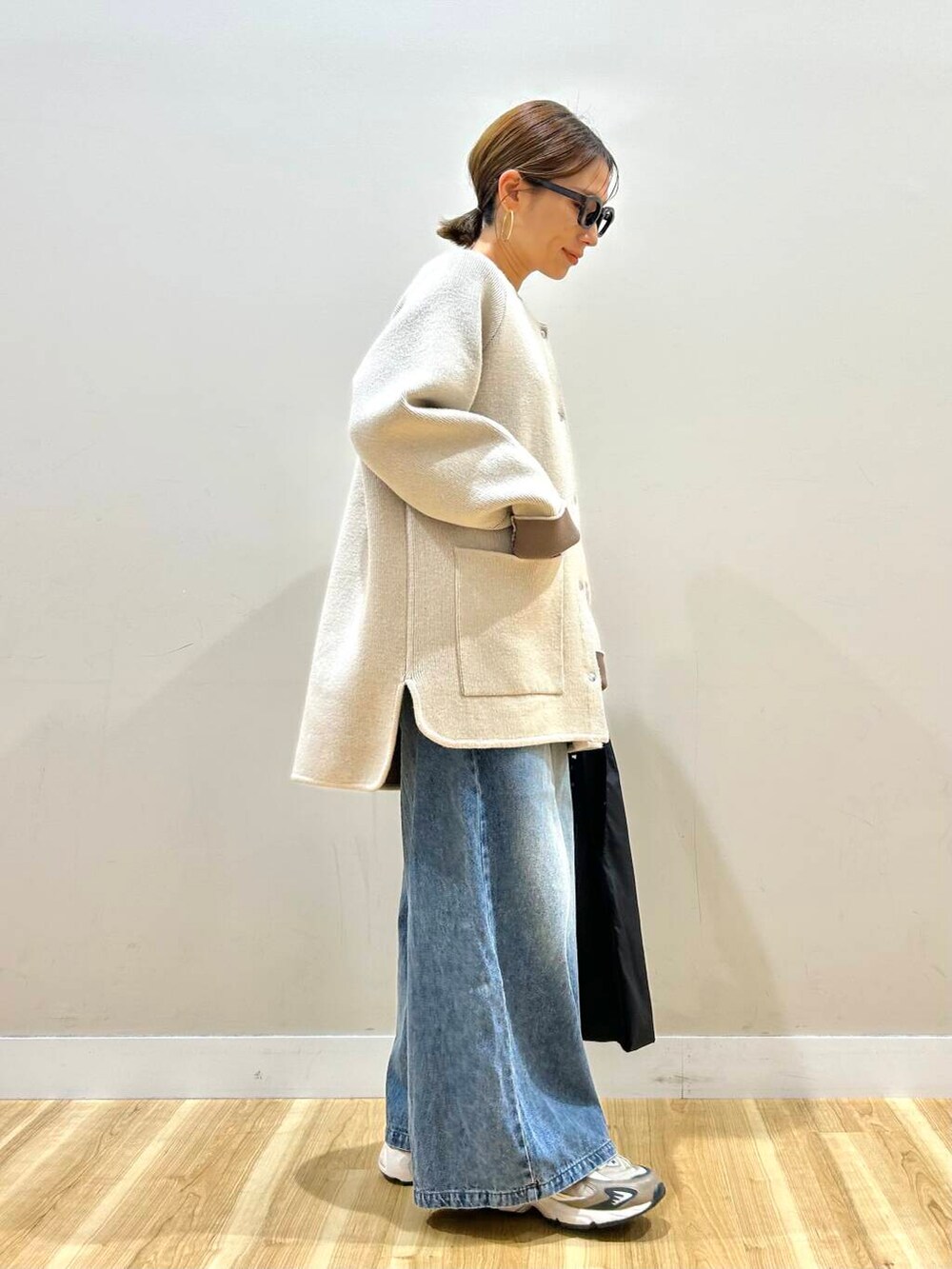 ホワイト系のニット/セーター、ブルー系のデニムパンツ、ブラック系のトートバッグを着用したレディースの春コーディネートの4枚目の写真