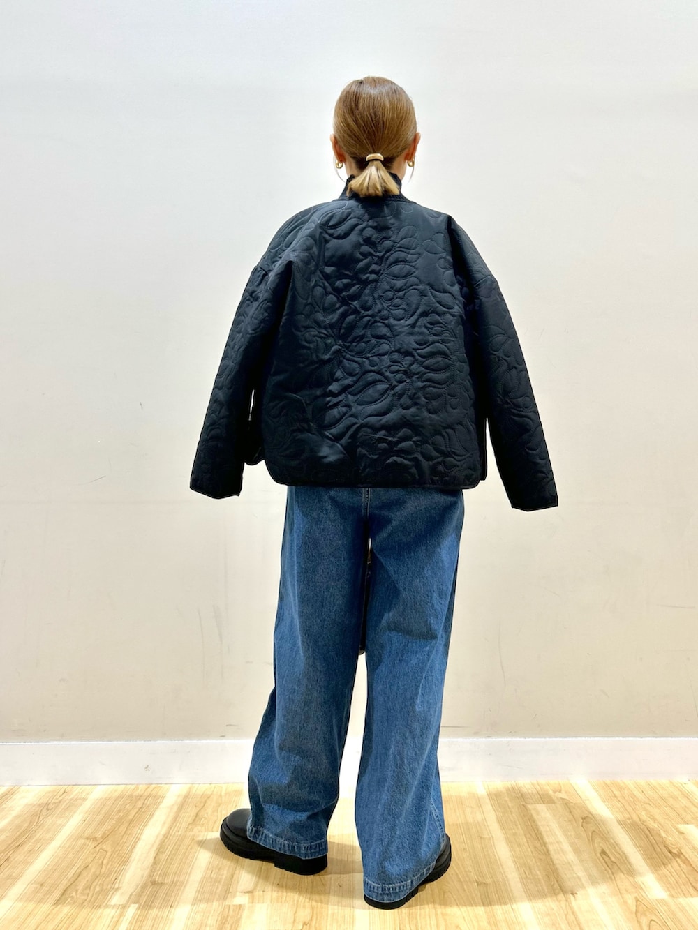 ブラック系のノーカラージャケット、ホワイト系のニット/セーター、ブルー系のデニムパンツを着用したレディースの秋コーディネートの3枚目の写真