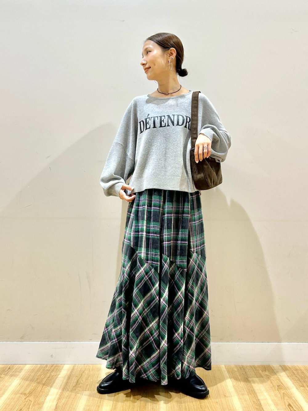 グレー系のニット/セーター、ブラウン系のハンドバッグ、グリーン系のスカートを着用したレディースの秋コーディネートの5枚目の写真