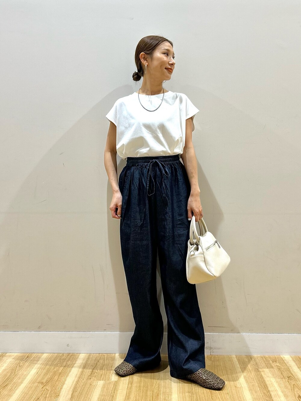 ホワイト系のTシャツ/カットソー、ブルー系のデニムパンツ、ブラウン系のハンドバッグを着用したレディースの春コーディネートの5枚目の写真