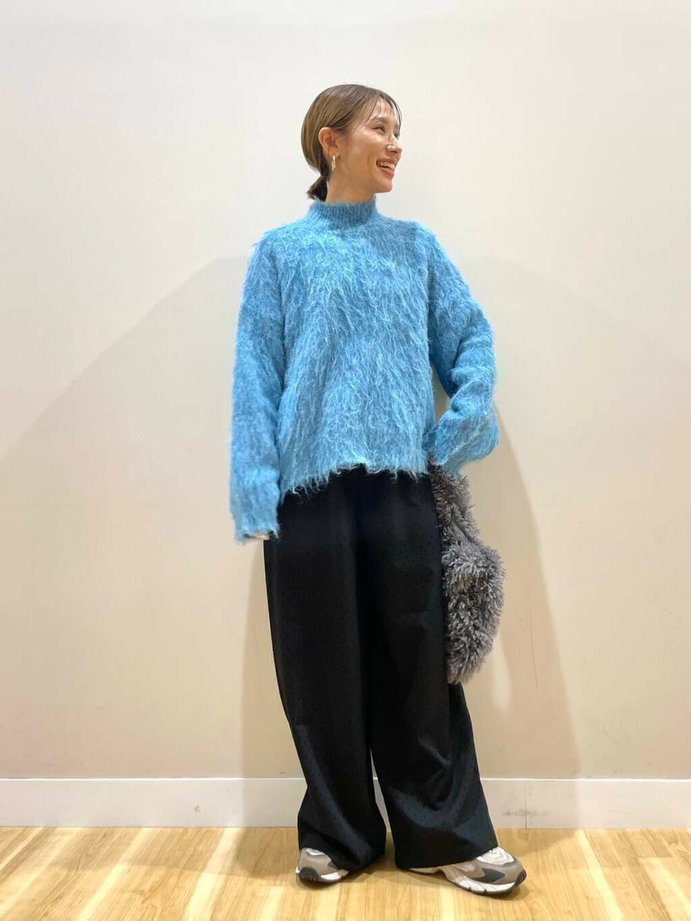 ブラック系のダウンジャケット/コート、ブルー系のニット/セーター、グレー系のハンドバッグを着用したレディースの冬コーディネートの2枚目の写真