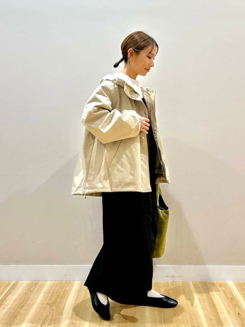 ゴールド系のトートバッグ、ベージュ系のマウンテンパーカー、ホワイト系のスウェットを着用したレディースの冬コーディネートの4枚目の写真